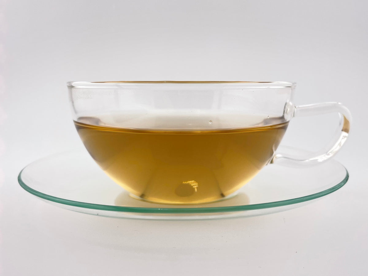 Clear glass teacup with tea on a white background